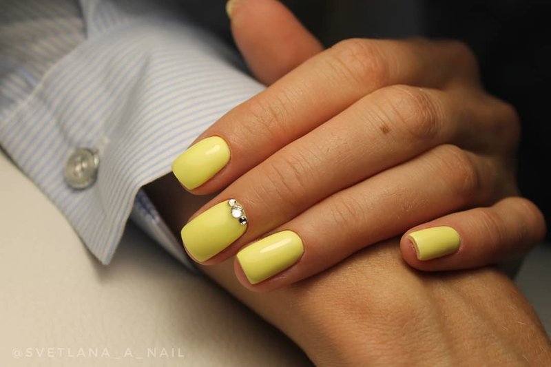 Delikatny żółty manicure z kryształkami.