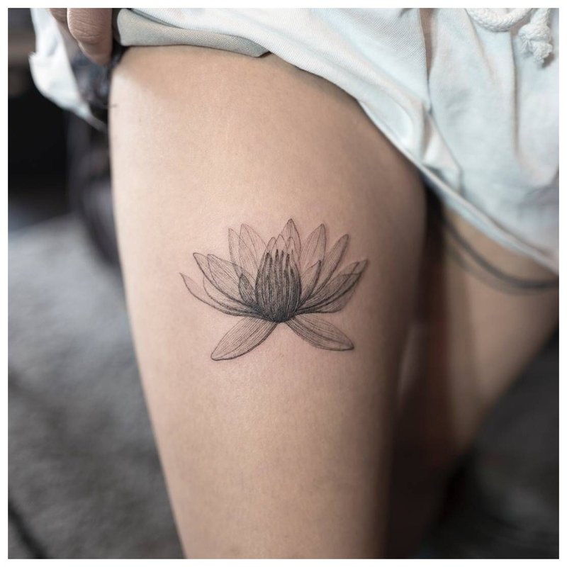 Delikatny kwiat - tatuaż na nodze dziewczyny