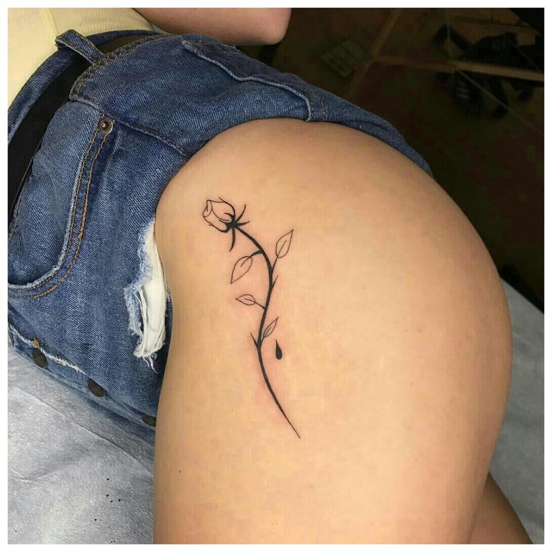 Tatuiruotė ant mergaitės klubo subtilios gėlės pavidalu