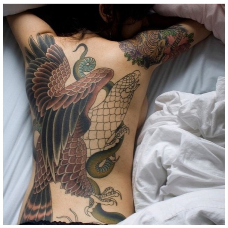 Mergaitė su rytietiška tatuiruote ant nugaros.