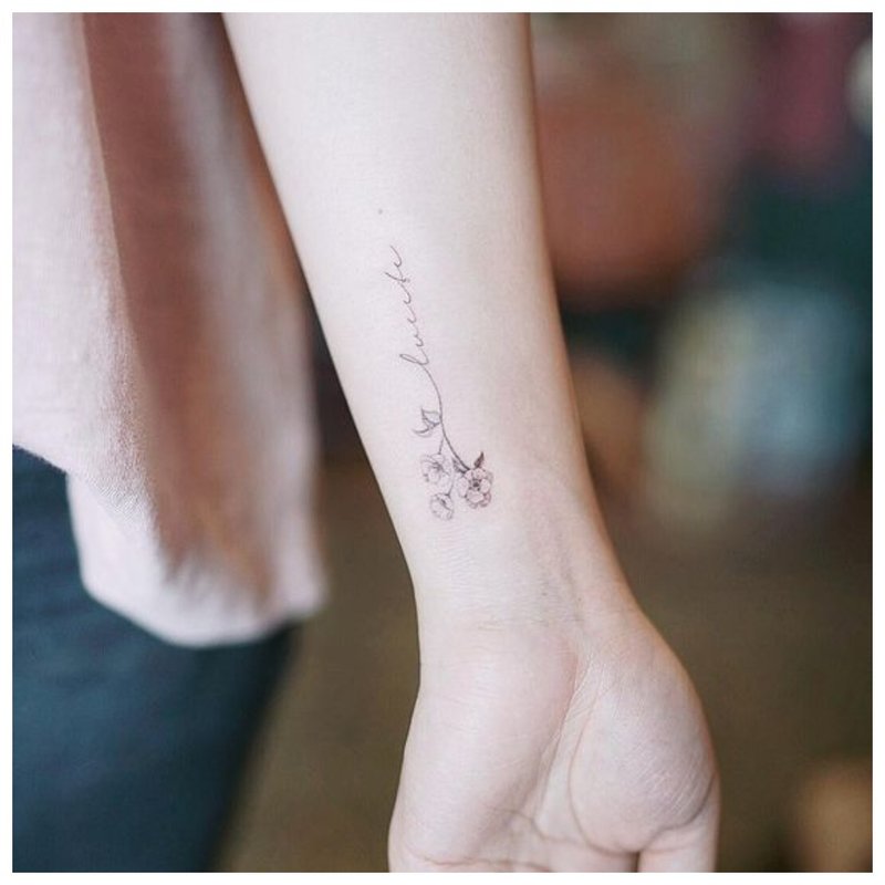 Bokstaver med blomster - tatovering på håndleddet
